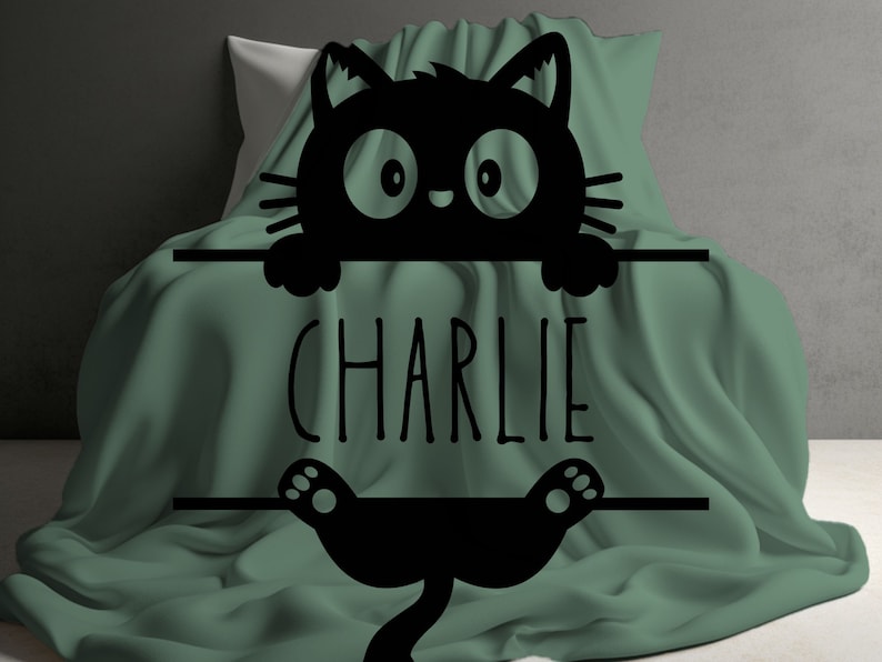 May include: A green blanket with a black cat silhouette peeking over the top. The cat is holding a sign that says "CHARLIE".