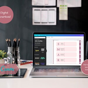 May include: A digital download of a printable planner template with the acronym "SMART" written in pink on a pink background. The template is designed to be edited in Canva and includes a PDF version. The image shows a laptop screen displaying the template, with a jar of pencils and a tablet on a white desk.