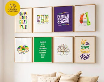 May include: A collection of framed art prints with gold frames, featuring colorful text and illustrations. The prints include phrases like "Happy Mardi Gras Y'all!" and "Carnival Season." The artwork is displayed above a purple sofa with decorative pillows.