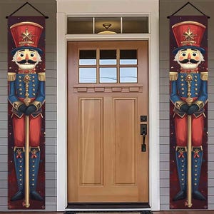May include: Two vertical rectangular banners featuring a nutcracker soldier illustration. The nutcracker wears a red hat with a gold star, a blue jacket with gold stars and epaulets, and red trousers. It holds a long gold staff in its hands.