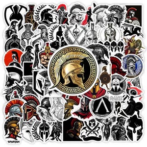 May include: A collection of stickers featuring various Spartan helmet designs, warriors, and emblems in black, white, red, and gold. The stickers vary in size and shape, with a central sticker showcasing a golden helmet.