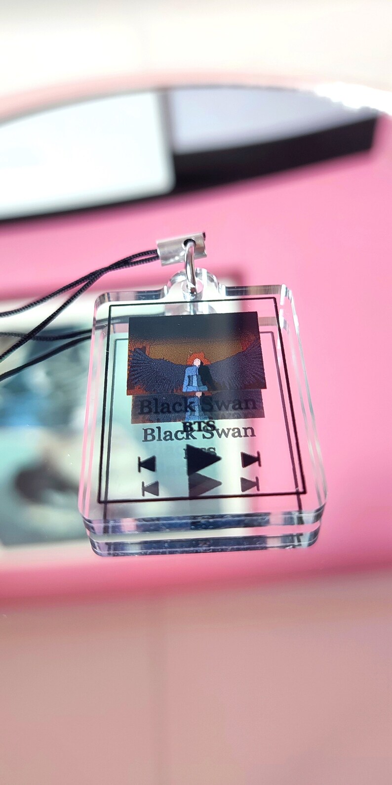 May include: A clear acrylic keychain with a black and white image of a person with wings. The text "Black Swan BTS Black Swan" is printed on the keychain.