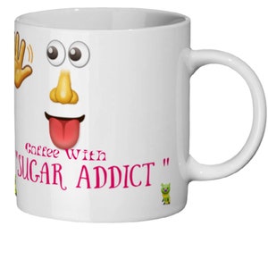 Peut inclure: Une tasse à café en céramique blanche avec un visage de dessin animé et le texte "Coffee With "Sugar Addict"" en rose.