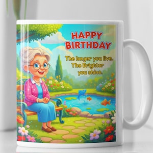 Pode incluir: Caneca de cerâmica branca com uma ilustração de desenho animado de uma mulher idosa sentada em um banco de parque. A caneca tem o texto "HAPPY BIRTHDAY" e "The longer you live, The Brighter you shine."