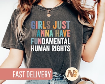 Peut inclure: Un t-shirt gris foncé avec le texte "Girls Just Wanna Have Fundamental Human Rights" en lettres colorées.