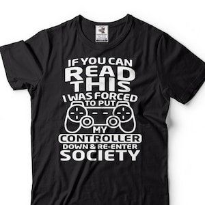 May include: Black t-shirt with white text that reads "If you can read this I was forced to put my controller down & re-enter society". The text is accompanied by a white graphic of a video game controller.