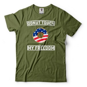 May include: A green t-shirt with the text "Donut Touch My Freedom" in white. A donut with an American flag design is in the center of the shirt.