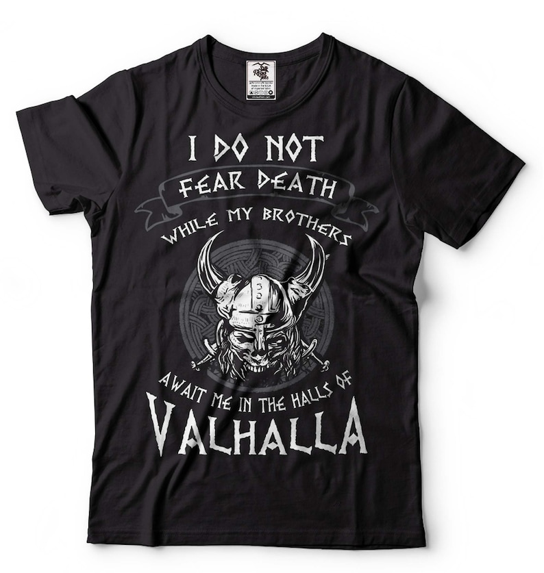 Puede incluir: Camiseta negra con un dise&ntilde;o gr&aacute;fico blanco que representa una calavera de guerrero vikingo con cuernos y el texto "No temo a la muerte mientras mis hermanos me esperan en las salas de Valhalla".