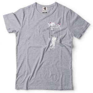 May include: A gray t-shirt with a white pocket and three white cats drawn on it. The cats are peeking out of the pocket, with one hanging from the top of the pocket.