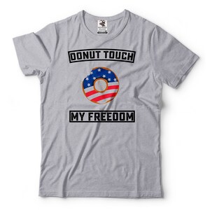 May include: Gray t-shirt with the text "Donut Touch My Freedom" in black. A donut with an American flag design is in the center of the shirt.