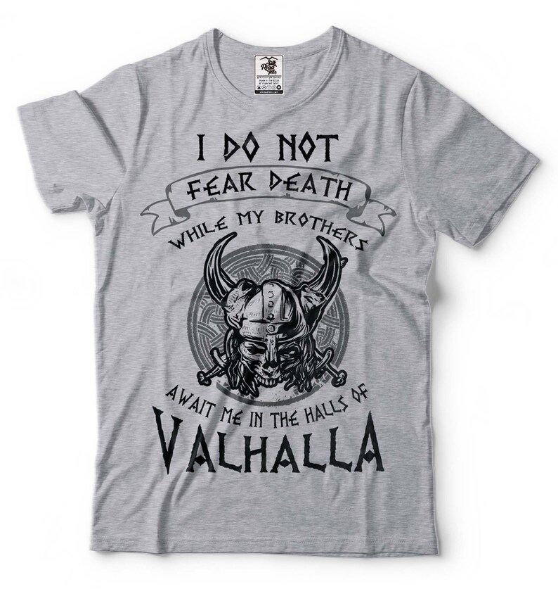 Puede incluir: Camiseta gris con un dise&ntilde;o gr&aacute;fico en blanco y negro de un casco vikingo con cuernos y el texto "No temo la muerte mientras mis hermanos me esperan en las salas de Valhalla".