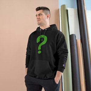 Könnte beinhalten: Schwarzer Kapuzenpullover mit einem grünen Fragezeichen-Motiv. Das Fragezeichen besteht aus einer Reihe von Linien und Punkten.