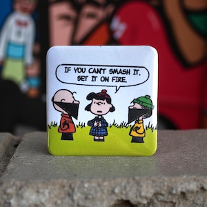 May include: Square button with a cartoon image of three characters wearing black masks, standing on green grass. The button has the text "IF YOU CAN'T SMASH IT. SET IT ON FIRE."