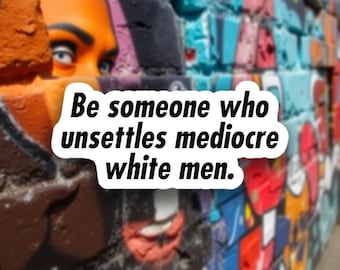 May include: A colorful graffiti wall with a portrait and text that reads "Be someone who unsettles mediocre white men." The artwork features a mix of colors, including orange, blue, red, and black, creating a vibrant urban aesthetic.