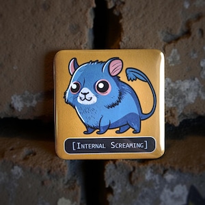 Könnte beinhalten: Quadratischer Button mit einer Cartoon-Kreatur in Blau mit rosa umrandeten Augen und einem langen Schwanz. Der Button hat den Text "[INTERNAL SCREAMING]" in Weiß auf goldenem Hintergrund. Der Button befindet sich vor einer Backsteinmauer.