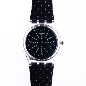 May include: A black Swatch watch with a silver case and a black polka dot band. The watch face has a black background with white dots.