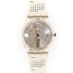 Könnte beinhalten: Eine transparente Swatch-Uhr mit Kalenderarmband. Das Zifferblatt der Uhr ist silberfarben mit schwarzen Ziffern und Zeigern. Das Armband zeigt die Monate Mai, Juni und Juli mit den entsprechenden Daten.