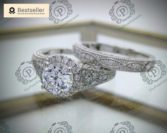 May include: A silver engagement ring set with a large round center stone surrounded by smaller stones. The band is decorated with a delicate filigree design.
