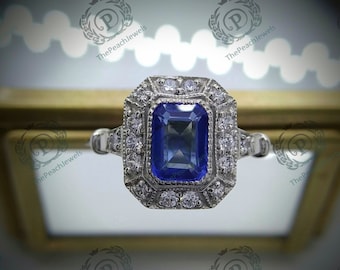 May include: A silver ring with a large, square-shaped blue sapphire gemstone surrounded by smaller diamonds. The ring has a vintage-inspired design with intricate details.