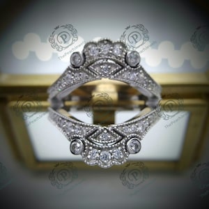 Op de afbeelding: Een zilveren ringsetting met een delicaat ontwerp met een rij kleine diamanten en drie grotere ronde diamanten. De setting is ontworpen om een ​​middelste steen te houden.