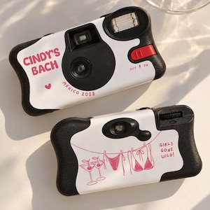 May include: Two disposable cameras with black and white bodies. The top camera features pink text reading CINDY'S BACH and MEXICO 2028 with a heart. The bottom camera displays a pink line drawing of two martini glasses, a bikini, and GIRLS GONE WILD.