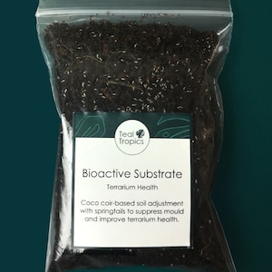 May include: A clear plastic bag filled with dark brown soil and white springtails. The bag has a label that reads "Teal Tropics Bioactive Substrate Terrarium Health Coco coir-based soil adjustment with springtails to suppress mould and improve terrarium health."
