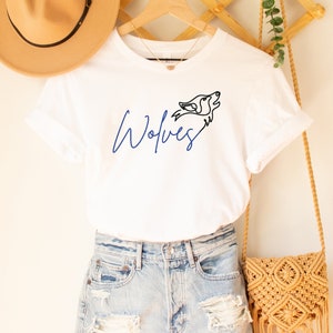 May include: White t-shirt with a blue "Wolves" graphic and a black line drawing of a wolf's head.