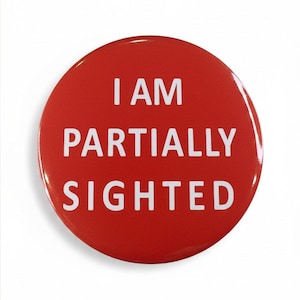 May include: A circular, red badge with the white text "I AM PARTIALLY SIGHTED". The badge has a shiny finish and a straightforward design. The text is centrally aligned and clear.