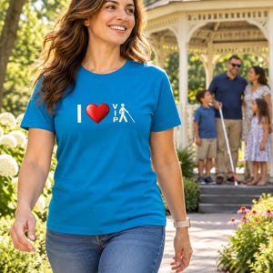 Op de afbeelding: Een felblauw T-shirt met korte mouwen en een grafische print op de borst. Het ontwerp bevat de letter I, een rood hartsymbool en de tekst VIP naast een wit icoon van een stokfiguur die een witte taststok voor slechtzienden vasthoudt.