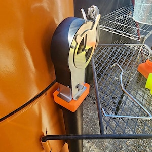 May include: A close-up of a black and silver metal smoker with an orange plastic base. The smoker has a round, silver dial with a black handle. The smoker is attached to a black metal pipe.