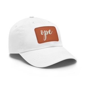 May include: White cotton baseball cap with a brown leather patch that says "ope" in white cursive lettering.