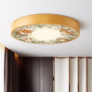 May include: A round flush mount ceiling light fixture with a light wood grain frame. The circular diffuser features a printed illustration of a fox, a deer, a rabbit, and an owl surrounded by green foliage, small flowers, and acorns on a cream background.