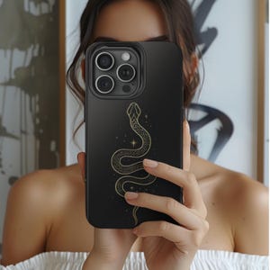 May include: Black phone case with a gold snake design. The snake is curled up and has a star behind it.