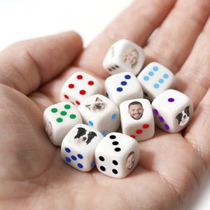 May include: A collection of white dice with various faces and dot patterns. Some dice feature images of a person, a cat, and a dog. The dots are in red, green, blue, and purple.