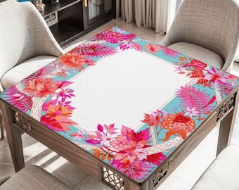 May include: A square wooden table with a floral patterned top. The design features pink, orange, and red flowers with turquoise accents. The table is surrounded by chairs with light gray upholstery.