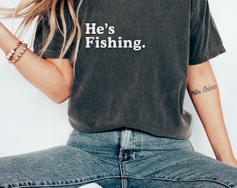 Maglietta con colori confortevoli "He's Fishing": divertente regalo per la moglie del pescatore