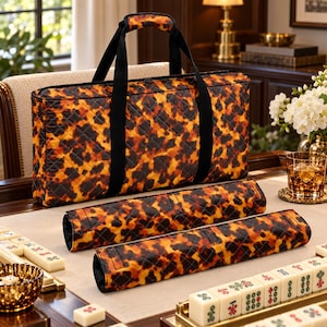May include: A rectangular quilted carrying bag and two matching rectangular quilted sleeves, all featuring a brown and black tortoiseshell pattern. The bag has black fabric handles and a top zipper closure, while the sleeves are elongated.