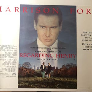 May include: Movie poster for "Regarding Henry" starring Harrison Ford. The poster features Ford's portrait above a scene of a man, woman, and child in a park. Text includes the film's title, director, and cast.