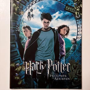 May include: A film poster for "Harry Potter and the Prisoner of Azkaban" showing the main characters in front of a portal. The title is in a stylized font, with a dark blue and green background.