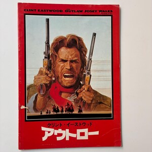 May include: A vintage movie poster for "Outlaw Josey Wales" featuring Clint Eastwood. The poster has a red border and displays Eastwood holding two guns, with Japanese text at the bottom. The background shows a scene with riders on horseback.