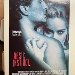 Może przedstawiać: Plakat filmowy do filmu "Instinct" z udziałem Michaela Douglasa i Sharon Stone. Plakat przedstawia zbliżenie dwóch aktorów w namiętnym uścisku. Tytuł filmu jest napisany dużymi, pogrubionymi literami na dole plakatu.