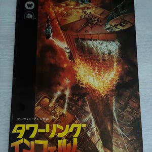 May include: A vintage movie poster for "The Towering Inferno" featuring a burning skyscraper. The artwork depicts a dramatic scene with helicopters, people, and flames engulfing the building. The title is in both English and Japanese.