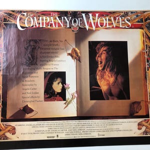 Könnte beinhalten: Ein Filmplakat für den Film "The Company of Wolves" mit Angela Lansbury und David Warner. Das Plakat hat eine dunkle, gotische Ästhetik mit einem rot-schwarzen Farbschema. Der Text auf dem Plakat lautet "The Company of Wolves" und "A Neil Jordan Film".