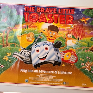 May include: A colorful poster for "The Brave Little Toaster" animated film. The artwork features a smiling toaster, a boy, and other animated characters in a vibrant outdoor scene. Text includes the film's title and tagline: "Plug into an adventure of a lifetime."