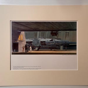 Könnte beinhalten: Ein gerahmter Druck des Millennium Falcon aus Star Wars. Das Bild zeigt das ikonische Raumschiff in einer Garage mit Charakteren in der Nähe. Der Druck ist mattiert und in einer neutralen Farbe gerahmt.