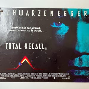 Puede incluir: Un póster de película para la película "Total Recall" protagonizada por Arnold Schwarzenegger. El póster presenta un primer plano de la cara de Schwarzenegger con el lema "Se robaron su mente, ahora la quiere de vuelta."