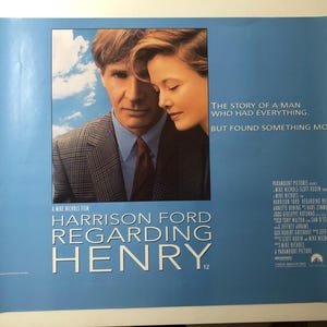 May include: A movie poster for "Regarding Henry" featuring Harrison Ford and Annette Bening. The poster has a blue background with the film's title in large white letters. The tagline reads, "The story of a man who had everything, but found something more."