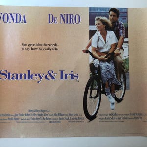 May include: A vintage film poster for "Stanley & Iris" starring Fonda and De Niro. The poster depicts a couple on a bicycle, with the film's title in a decorative font. The background has a sepia tone.