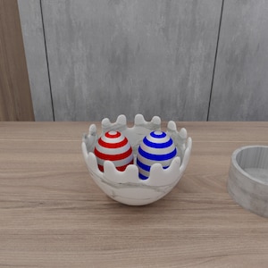 May include: Two striped decorative eggs, one red and white, the other blue and white, are nestled in a white ceramic bowl with a wavy rim.