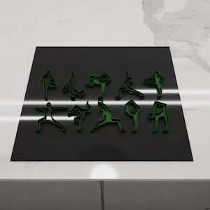 May include: A black surface with green yoga poses cut out of it. The poses are arranged in a row and include downward dog, warrior one, and tree pose.